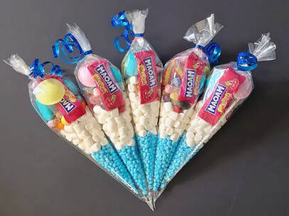 A colorful assortment of sweets and candies arranged in a transparent cone-shaped plastic bag, sealed with a blue ribbon at the top.