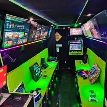 Inside the Streetside Gaming Bus with green seating, controllers and multiple gaming screens