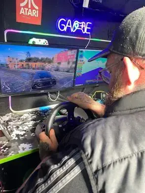 Adult using the racing simulator inside the Streetside Gaming Bus in Essex
