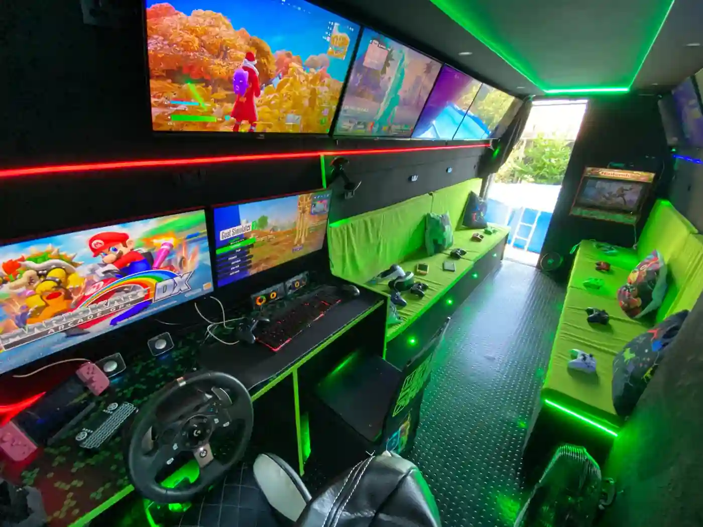 Inside the Streetside Gaming Bus in Colchester with gaming screens, consoles, racing simulator and neon LED lighting.