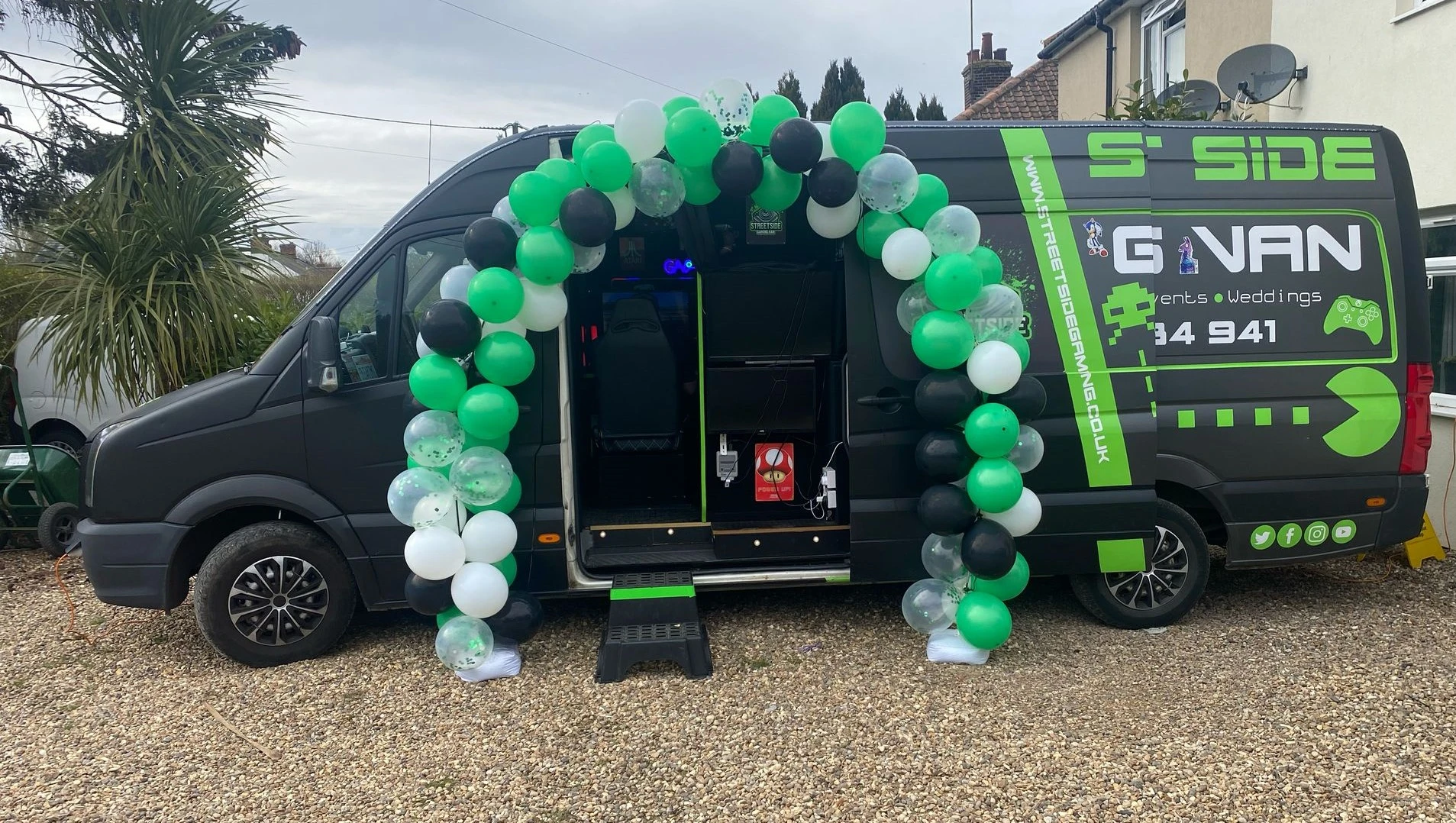 Streetside Gaming Bus decorated with a green, black and white balloon arch for a gaming party.