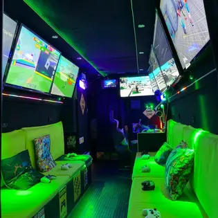 Inside the Streetside Gaming Bus with green seating, controllers and multiple gaming screens