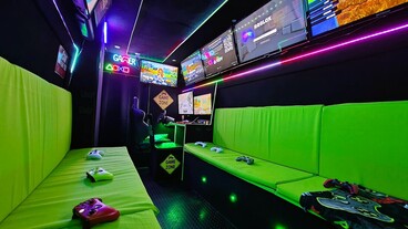 Inside the Streetside Gaming Bus in Southend-on-Sea with green seating, controllers and multiple gaming screens