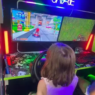 Child playing Mario Kart on the racing simulator inside the Streetside Gaming Bus.