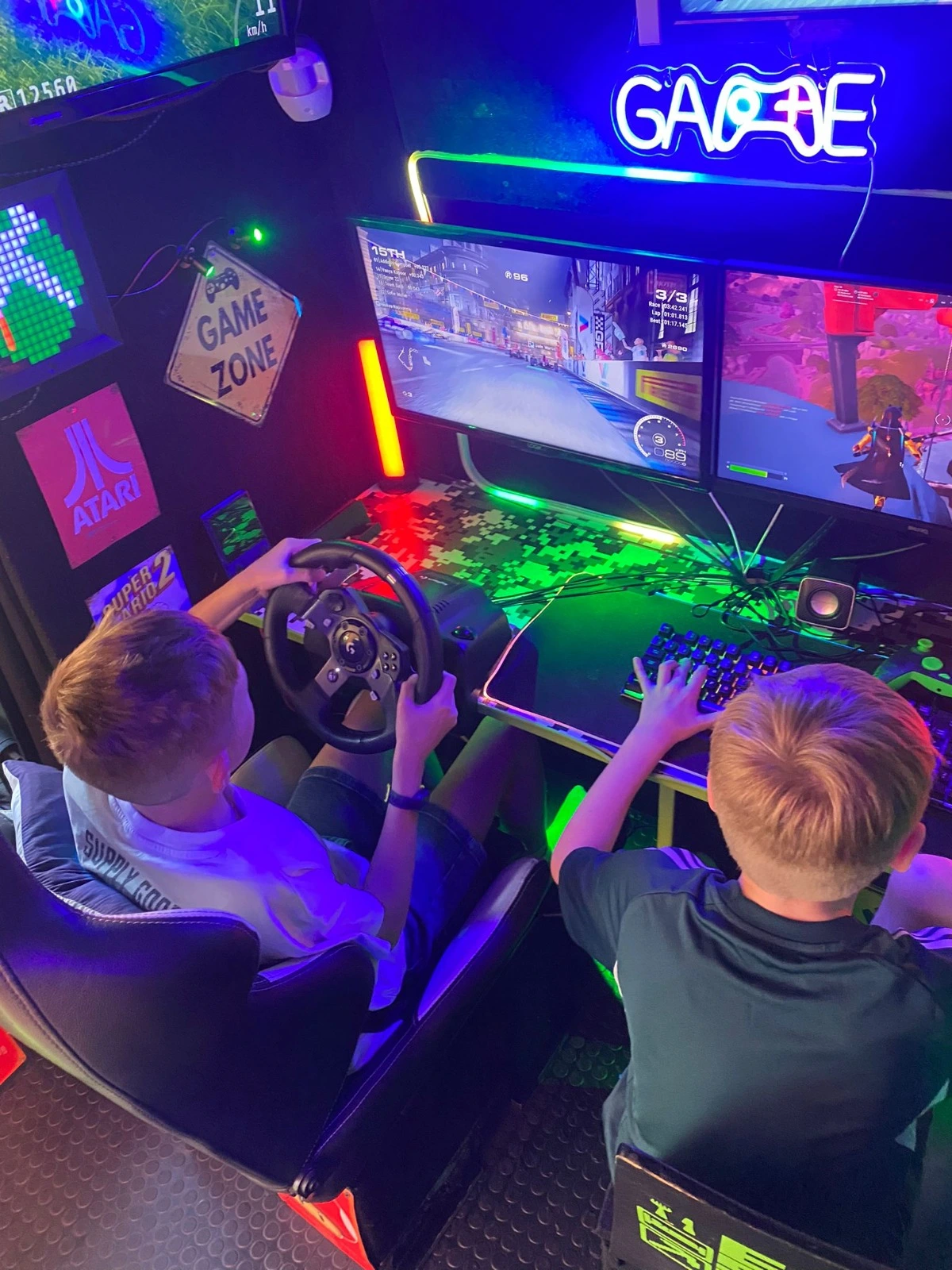 Two children playing a racing simulator and gaming PC inside the Streetside Gaming Bus.