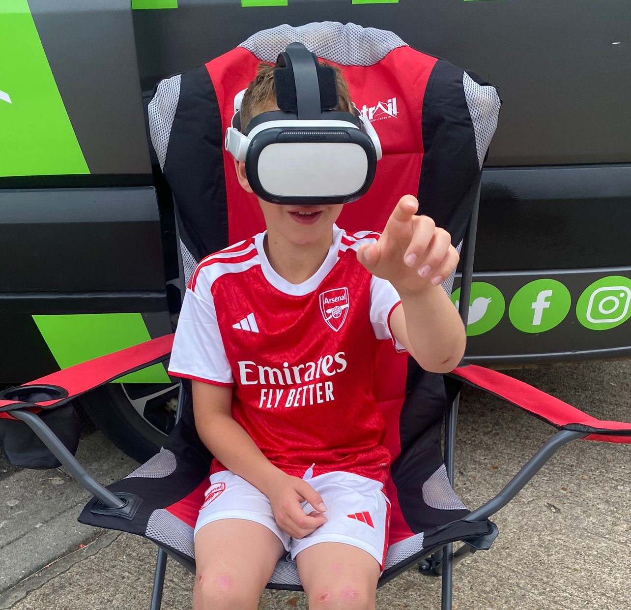 Child wearing a virtual reality headset beside the Streetside Gaming Bus.