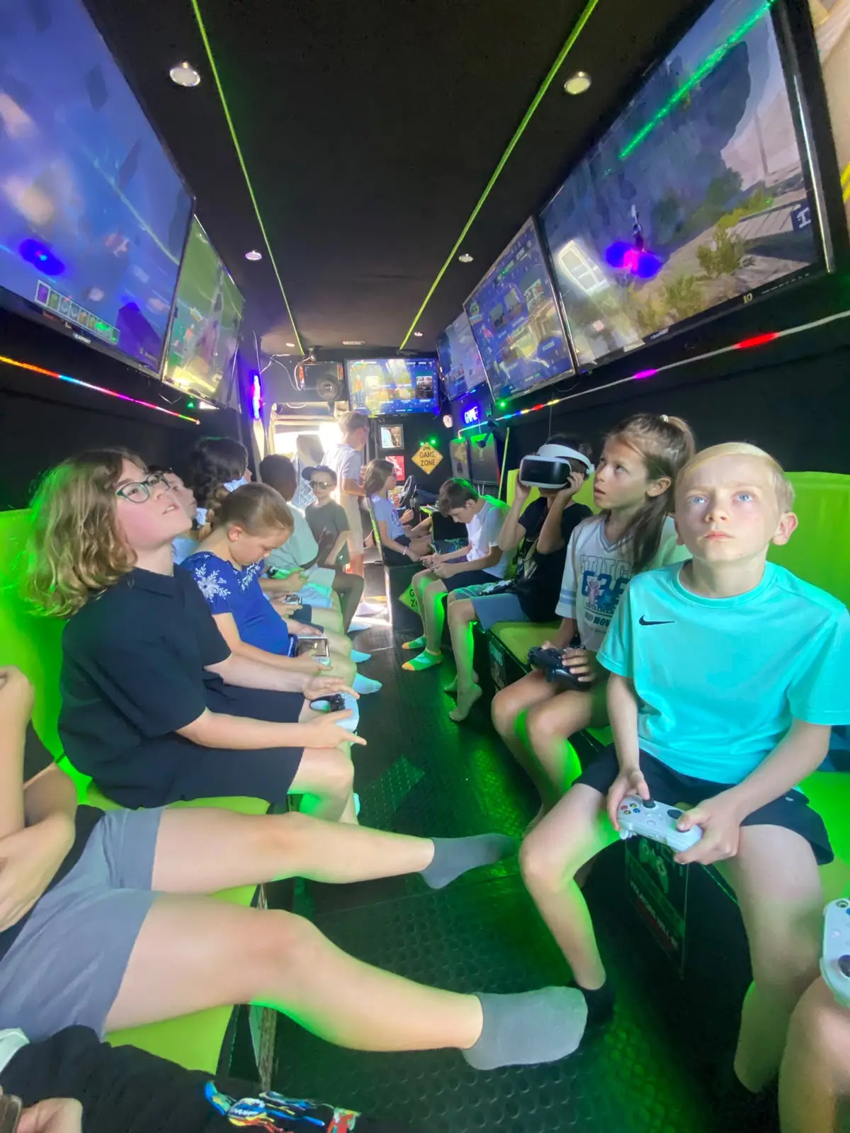 Children enjoying a gaming party inside the Streetside Gaming Bus with individual screens, consoles and VR