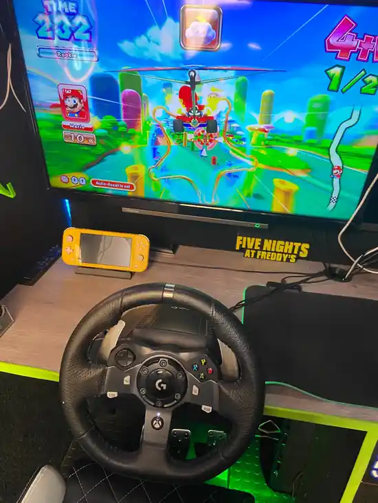 Mario Kart racing game with steering wheel setup inside the Streetside Gaming Bus